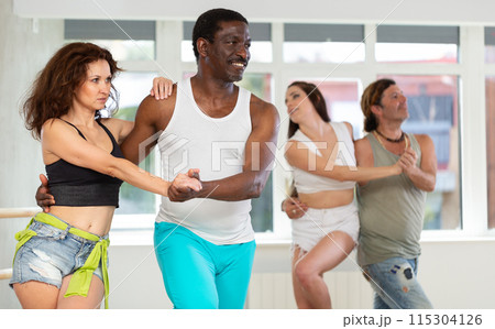 Brunette performing passionate kizomba with African American partner 115304126