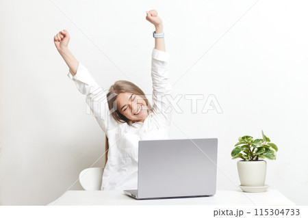 happy girl with laptop rejoices at successful work while working in the office, success at work 115304733