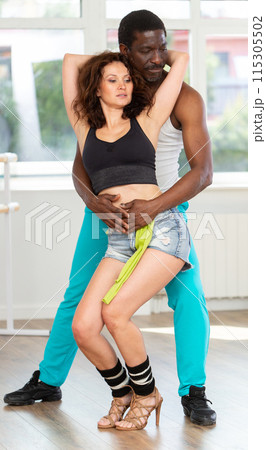 Woman dances incendiary tango with African man partner during choreography lesson 115305502