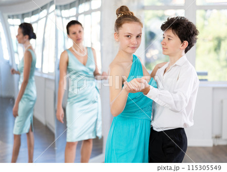 Experienced female dancer teaches tango to pair of teenagers in ballroom 115305549