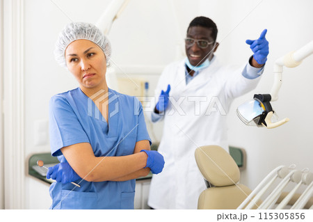 Doctor dentist is dissatisfied with the work of nurse 115305856