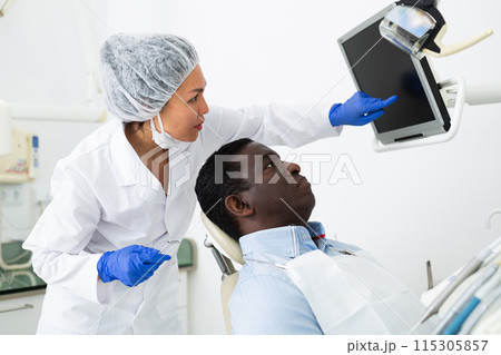 Doctor dentist shows the patient the result of dental x-ray 115305857