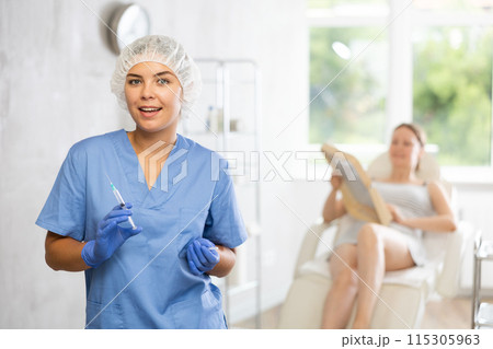 Nurse in disposable cap with syringe in hand and conducts preparatory activities before injections. 115305963