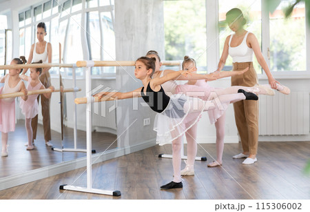 Little girls ballet lovers learn to perform arabesque pose in choreography studio Little girls ballet lovers learn to perform arabesque pose in choreography studio 115306002