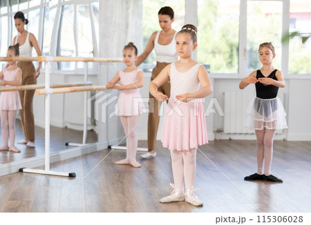 Girls in ballet class perform first position with correction of female mentor 115306028