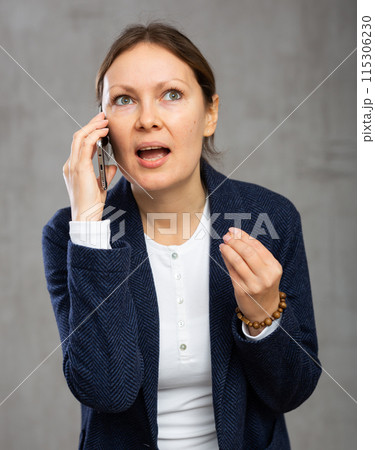 Indignant adult woman in jacket talking on phone Indignant adult woman in jacket talking on phone 115306230