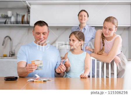 Joyful daughters surrounded dad in kitchen and asked for money Joyful daughters surrounded dad in kitchen and asked for money 115306256
