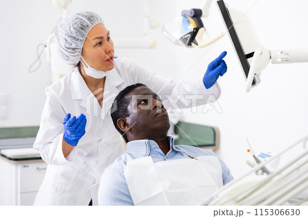 Doctor dentist shows the patient the result of dental x-ray Doctor dentist shows the patient the result of dental x-ray 115306630