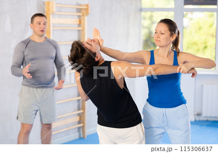 Guy paired up with woman to perform effective impact on pain points while learning self-defense. 115306637