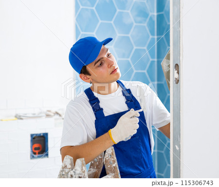 Young tiler working with ceramic tiles for interior decoration of repairable room 115306743