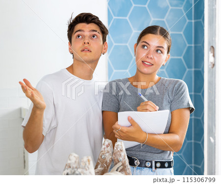 Young couple making notes while working on renovation of house 115306799