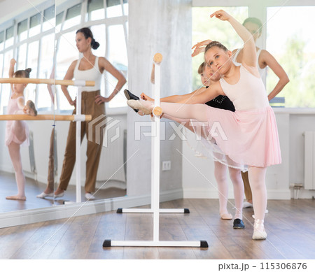 Little ballerinas together with choreography teacher in grand batman pose learn to dance ballet Little ballerinas together with choreography teacher in grand batman pose learn to dance ballet 115306876