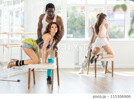 Brunette practicing chair dance with black partner in studio 115306906