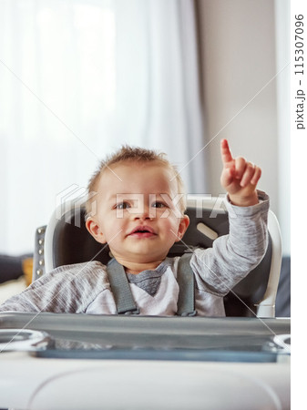 Baby, high chair and house in portrait for development or wellness, motor skills with finger for growth. Young, boy child and hand in home for healthy learning, waiting for meal time in apartment Baby, high chair and house in portrait for development or wellness, motor skills with finger for growth. Young, boy child and hand in home for healthy learning, waiting for meal time in apartment 115307096