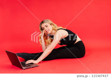 Happy young female do exercises before laptop screen at home or in gymnastic studio. 115307437