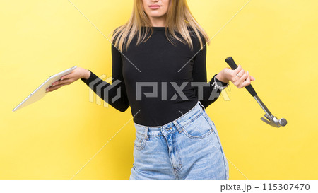 Attractive blond hair woman wearing business suit in front of a computer holding a hammer Attractive blond hair woman wearing business suit in front of a computer holding a hammer 115307470
