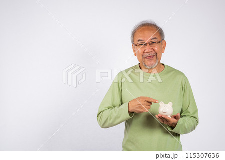 Portrait Asian older man points to a white piggy bank holding on hand studio shot isolated on white background. Concept of responsibility and financial planning, Saving money After retirement Portrait Asian older man points to a white piggy bank holding on hand studio shot isolated on white background. Concept of responsibility and financial planning, Saving money After retirement 115307636