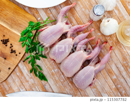 Raw quails with greens and spices prepared for cooking on wooden table Raw quails with greens and spices prepared for cooking on wooden table 115307782