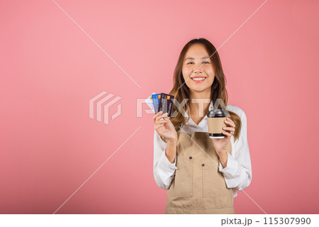 Portrait Asian happy young woman barista bar tender coffee maker holding coffee tea hot cup and credit card studio shot isolated on pink background, female smiling hold takeaways cup for payment Portrait Asian happy young woman barista bar tender coffee maker holding coffee tea hot cup and credit card studio shot isolated on pink background, female smiling hold takeaways cup for payment 115307990