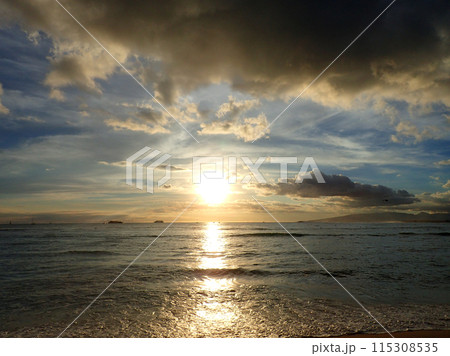 Sunset over the Waters of Waikiki with boats in the ocean and clouds in the air 115308535
