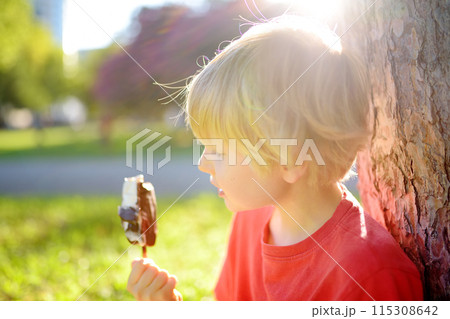 Happy little boy enthusiastically eating tasty ice cream outdoors in summer. Happy little boy enthusiastically eating tasty ice cream outdoors in summer. 115308642