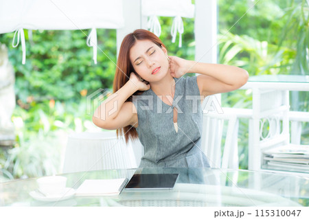 Young asian businesswoman massages neck while sitting at garden office. 115310047