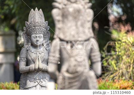 Stone statue of Buddha sitting on a stone pedestal surrounded by trees 115310460