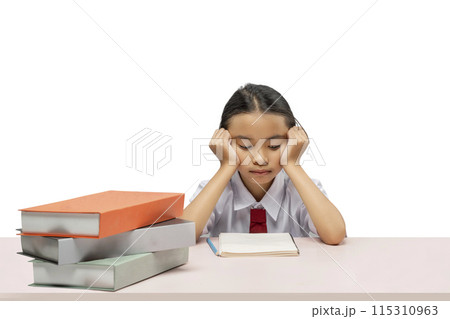 Portrait of an Asian elementary school student girl with a stack of books on the table tired of learning 115310963