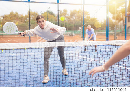 European young woman tennis player playing padel during friendly match on outdoor court in spring 115311041