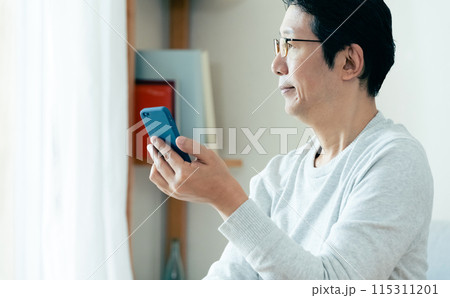 スマホをチェックするミドル男性 115311201