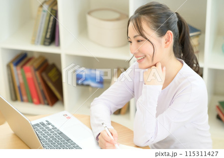 テーブルに座ってパソコンを操作する女性 115311427