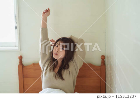 布団の上でくつろぐ女性 115312237