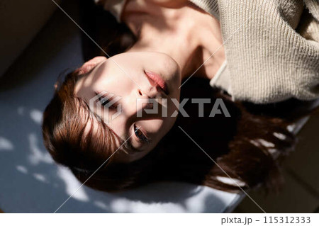 窓辺で日差しを浴びながら寝る女性 窓辺で日差しを浴びながら寝る女性 115312333