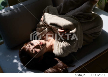 窓辺で日差しを浴びながら寝る女性 窓辺で日差しを浴びながら寝る女性 115312334