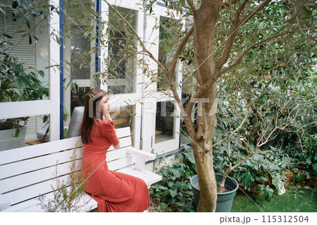 庭でくつろぐ若い女性のポートレート 115312504
