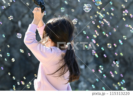 バブルガンでシャボン玉を楽しむ少女 115313220