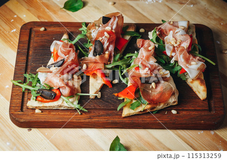 Culinary Delight: Prosciutto Bruschetta Trio on Cutting Board 115313259