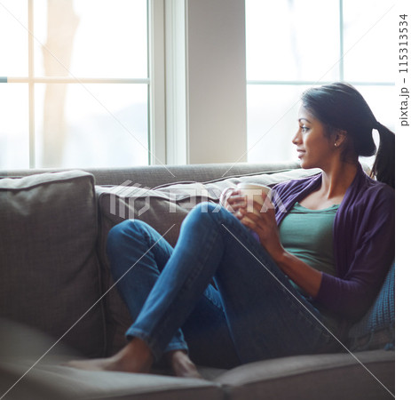 Thinking, relax and Indian woman drinking coffee in home living room for morning beverage, latte or espresso. Tea, dream and girl on sofa for peace, calm and planning future in comfortable house 115313534