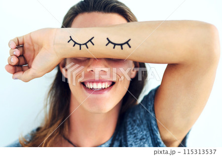 Person, happy and arm covering eyes with shy, eyelash and emoji isolated on white background. Playful, smile and joyful with hiding face, funny or embarrassed gesture with laugh expression in studio. 115313537