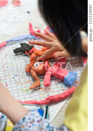 絵画教室で粘土を使った工作に励む小学生の子ども 115314097