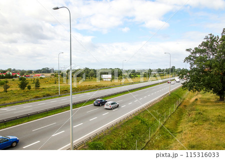 Highway with cars driving in summer, traffic on the road. Busy highway with vehicles moving in summer, traffic scene. Concept of speed and journey in transportation 115316033