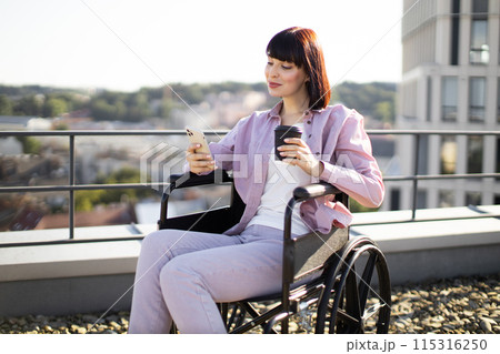 Woman in wheelchair holding coffee and smartphone on rooftop Woman in wheelchair holding coffee and smartphone on rooftop 115316250