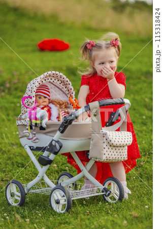 little girl plays with a doll and a stroller 115318424