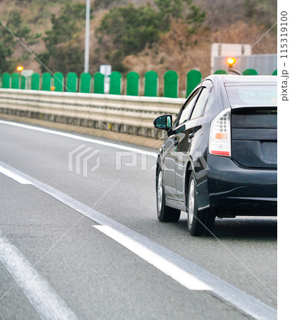 高速道路を追い越していく黒い乗用車 115319100