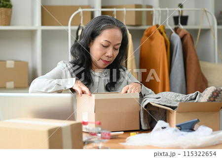 Mature woman packing boxes for delivery at her shop. Business online and e-commerce concept Mature woman packing boxes for delivery at her shop. Business online and e-commerce concept 115322654
