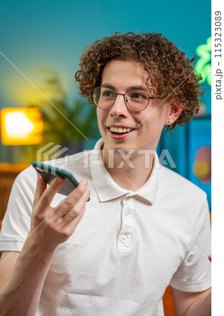 Happy Caucasian man making phone loudspeaker call conversation with friends talking gossip at home 115323089