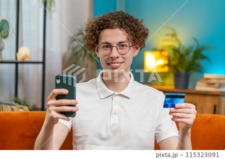 Man using credit bank card and smartphone while transferring money purchases online shopping at home 115323091