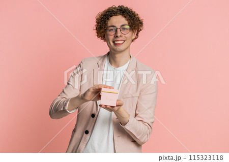 Smiling young man presenting jewelry gift present box stretches out hands promotion discount sale 115323118