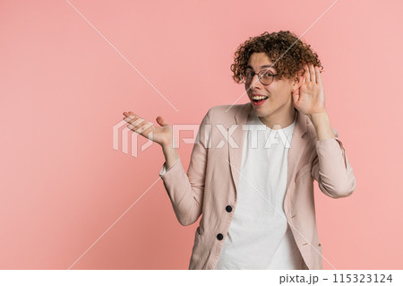 Caucasian man trying hear you looking confused and frowning, keeping arm near ear for louder voice 115323124