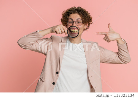 Happy smiling Caucasian man holding magnifier glass on teeth health care hygiene stomatology concept Happy smiling Caucasian man holding magnifier glass on teeth health care hygiene stomatology concept 115323134